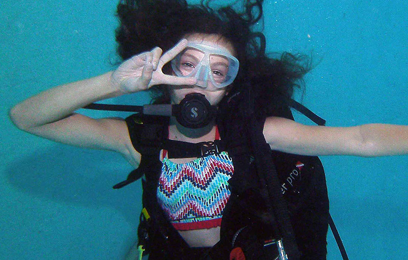 Young girl posing for a photo underwater at a try scuba experience.